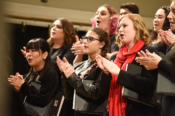 Photo of Chatham University music students standing on risers in a choir with music and matching black outfits. 